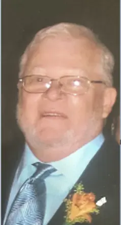 Elderly man wearing glasses and a formal suit.