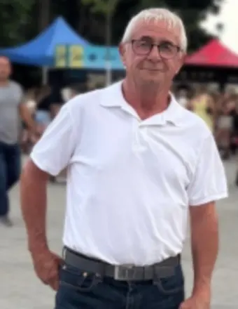 Older man in white shirt at outdoor event.