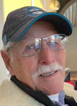 Elderly man with white mustache and glasses smiling