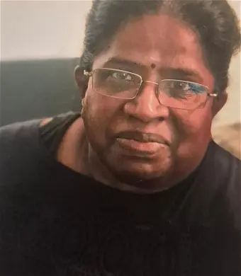 Person with glasses and bindi, looking at camera.