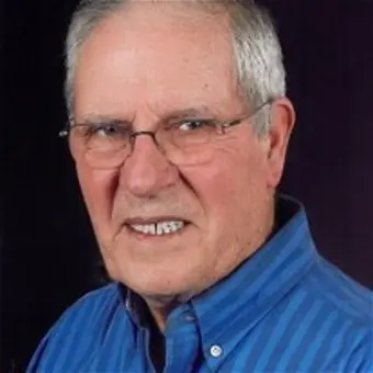 Elderly man smiling wearing a blue striped shirt