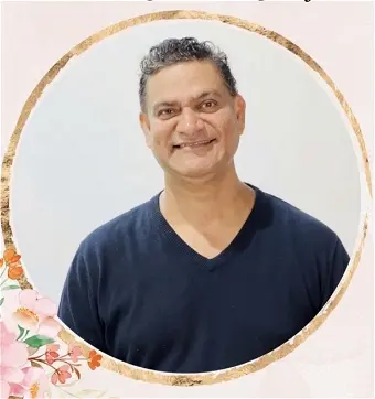 Smiling person in black shirt with floral frame.