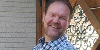 Smiling man in checkered shirt outdoors