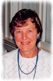 Smiling person wearing white sweater and blue necklace.