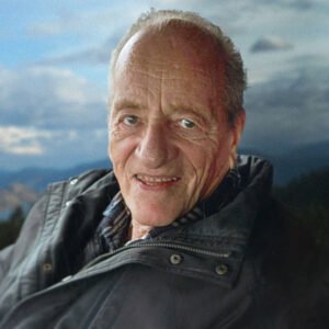 Elderly man smiling with cloudy sky background