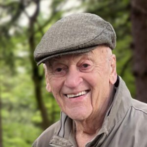 Smiling elderly man wearing a cap outdoors.