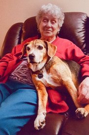 Elderly woman with dog on her lap reclining.