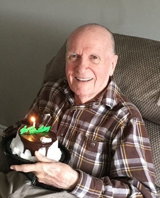 Smiling man holding chocolate birthday cake.