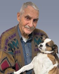 Elderly man with colorful sweater holding a dog.