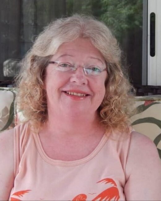 Smiling woman with curly hair on patio chair.
