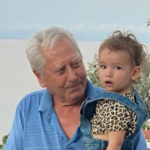 Elderly man holding a toddler outdoors.