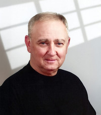 Man in black shirt smiling indoors.