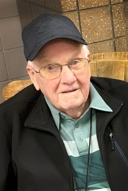Elderly man wearing a cap and jacket indoors.
