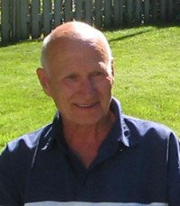 Elderly man smiling outdoors on sunny day.