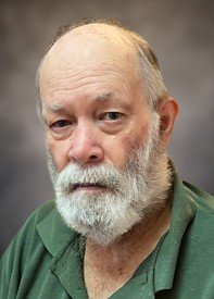 Bearded man in green shirt, serious expression