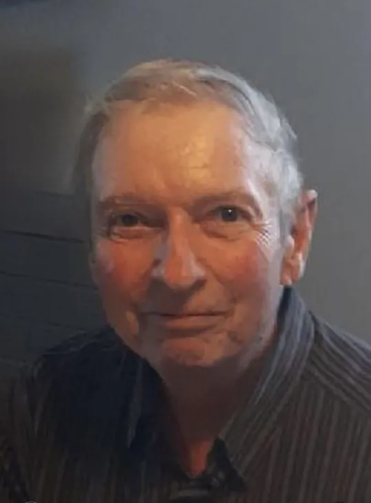 Smiling older man in striped shirt indoors.