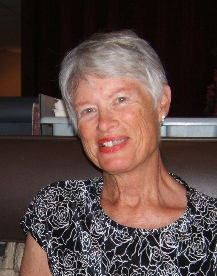 Smiling woman with short gray hair sitting indoors.
