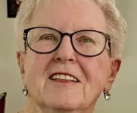 Smiling elderly person with glasses and earrings.