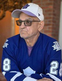 Man in blue jersey and cap looking concerned.