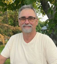 Smiling man outdoors with trees in background