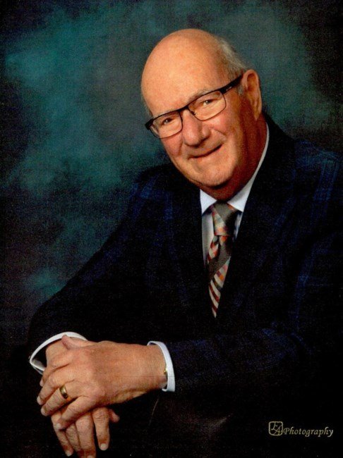 Elderly man in suit smiling, seated portrait.
