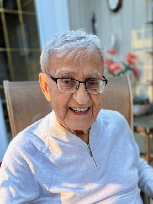 Smiling elderly man seated outdoors.