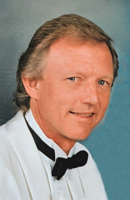 Smiling man in white tuxedo with bow tie.