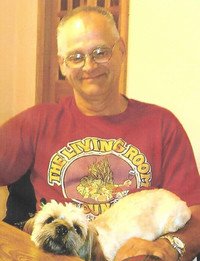 Man smiling with dog sitting on his lap.