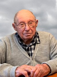 Elderly man sitting against a cloudy sky