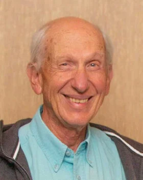 Elderly man smiling in casual attire.