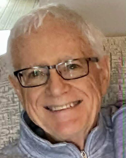Smiling man with glasses on a couch.