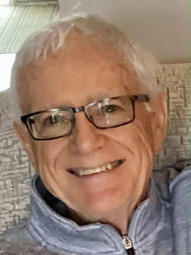 WRIGHT, Neil Harold Wright Smiling man with glasses on a couch.