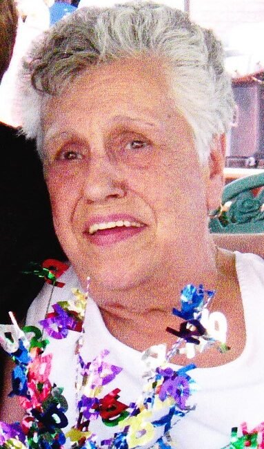 Smiling elderly woman holding colorful 80-year celebration decoration.