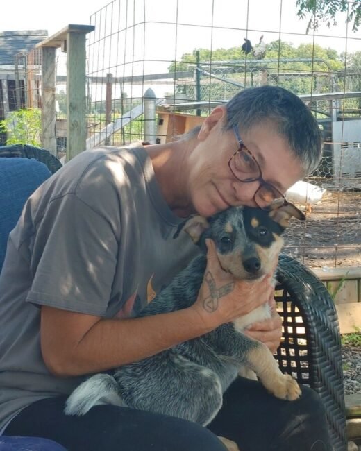 Person cuddling a small dog outdoors.