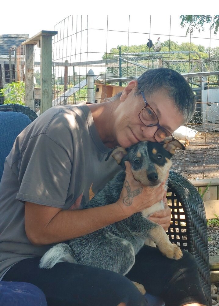 Person cuddling a small dog outdoors.
