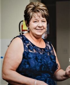 Smiling woman in a blue lace dress.
