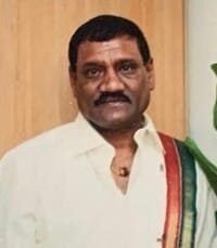 Man in traditional attire with mustache and sash.