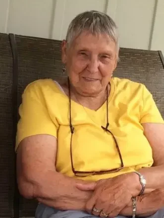 Elderly woman in yellow shirt sitting on a bench