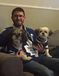 Person with dogs wearing sports jerseys on couch.