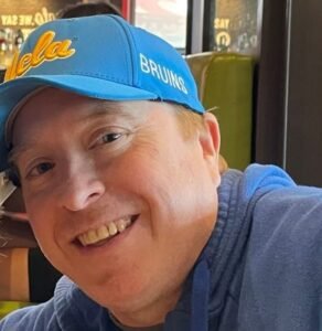 Person smiling wearing a blue UCLA hat.