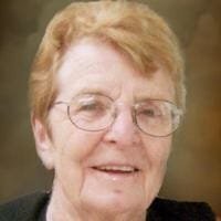 Elderly person smiling with glasses and short hair