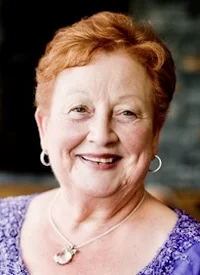 Smiling woman with short red hair and earrings.