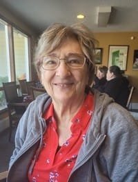 Smiling person in a restaurant wearing glasses.