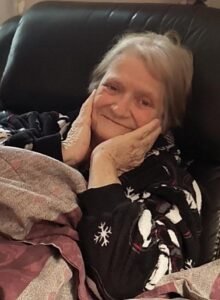 DESBIENS, Bonnie Jean Desbiens Smiling elderly woman relaxing on a couch.