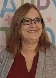 Smiling woman with glasses standing indoors