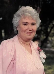 Elderly woman in pink dress with flowers outdoors