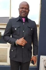 OPINDAS, Chukwuemeka Opindas Man in black suit with pink tie smiling
