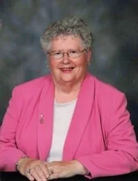 Smiling woman in pink blazer portrait.