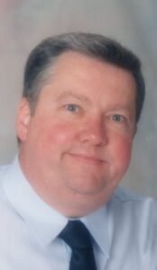 Middle-aged man with gray hair and a tie.