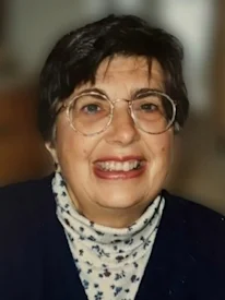 Smiling person with glasses and dark hair.